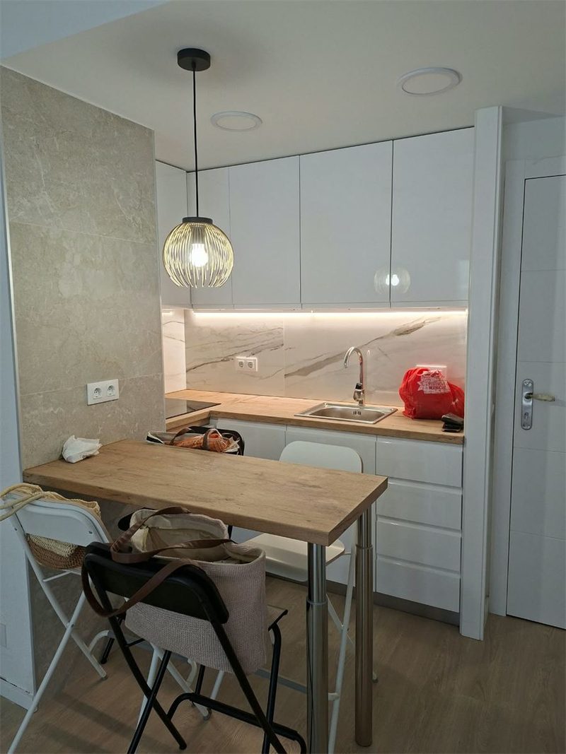Cocina reformada en Blanes, con muebles blancos y suelo de madera